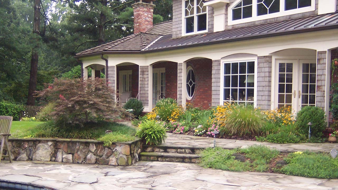 A landscaped back yard with stone walls and a stone patio area